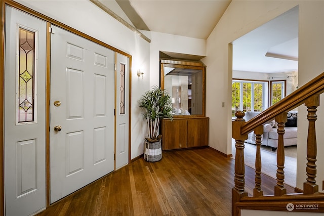 foyer with dark wood-style floors, vaulted ceiling, and stairs