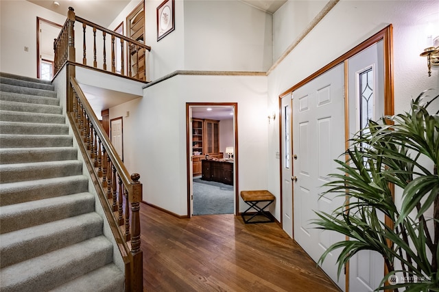 foyer with stairway, wood finished floors, and a towering ceiling