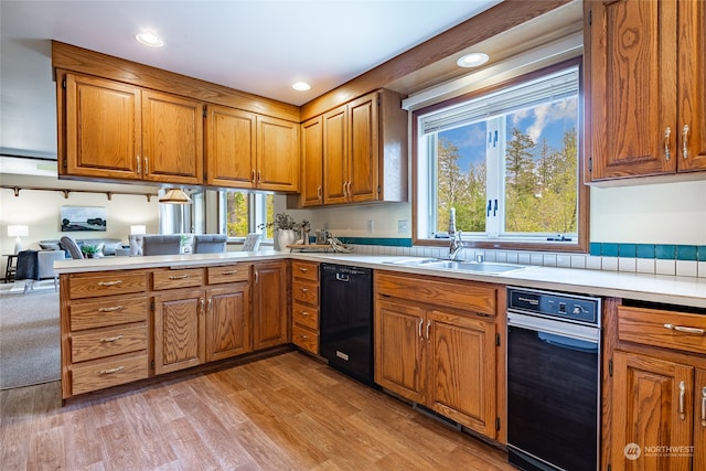 kitchen with a sink, light wood-style floors, black dishwasher, light countertops, and brown cabinetry