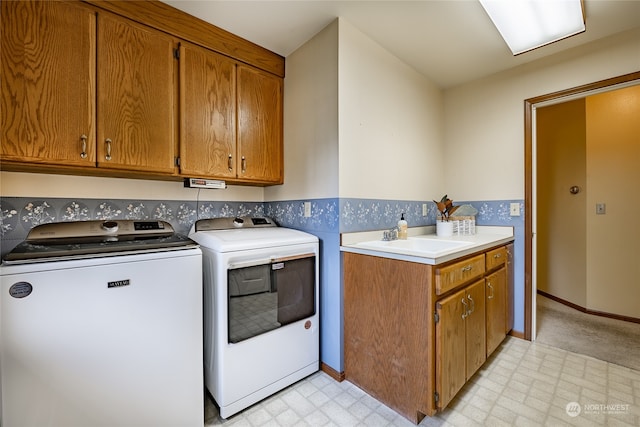 laundry room featuring light floors, cabinet space, washing machine and dryer, a sink, and baseboards