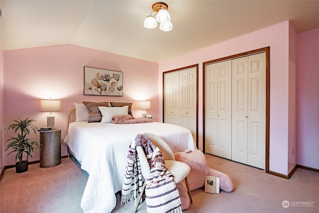 bedroom with carpet floors, baseboards, multiple closets, and lofted ceiling