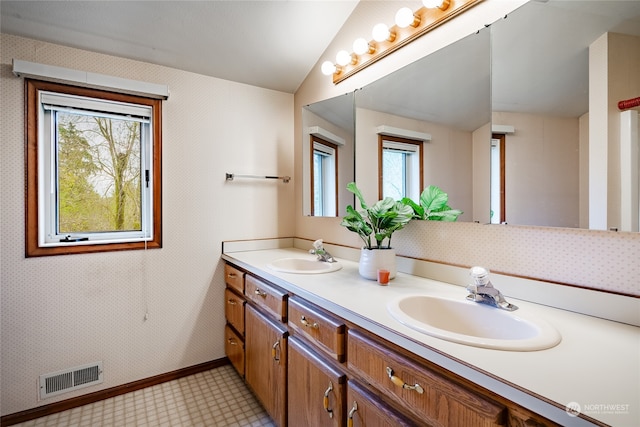 bathroom featuring lofted ceiling, double vanity, a sink, and visible vents