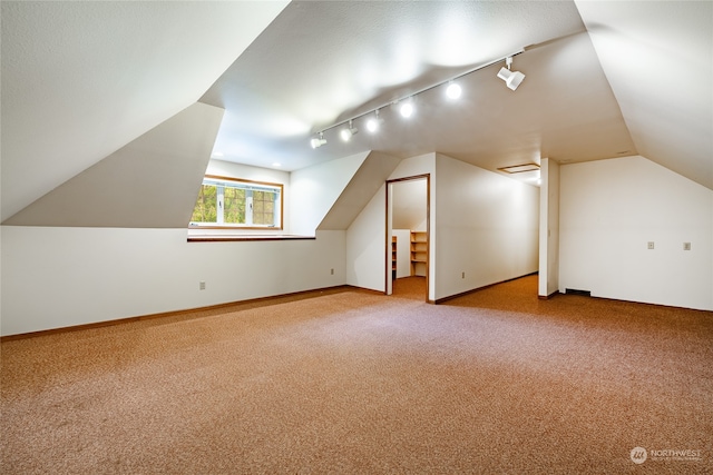 additional living space with baseboards, vaulted ceiling, and light colored carpet