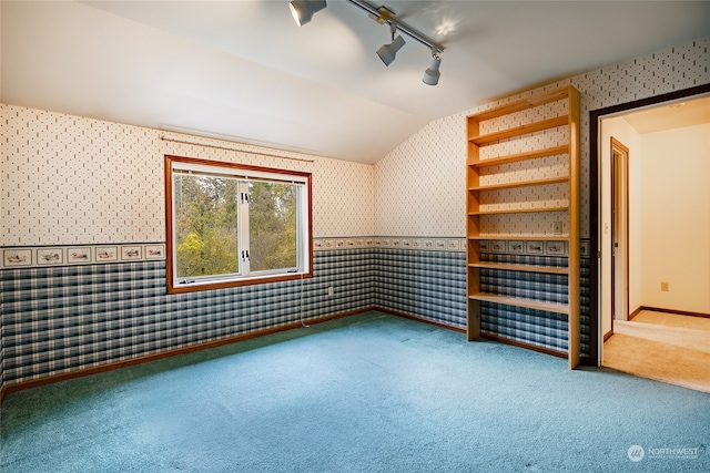 carpeted spare room featuring wallpapered walls, baseboards, vaulted ceiling, and track lighting