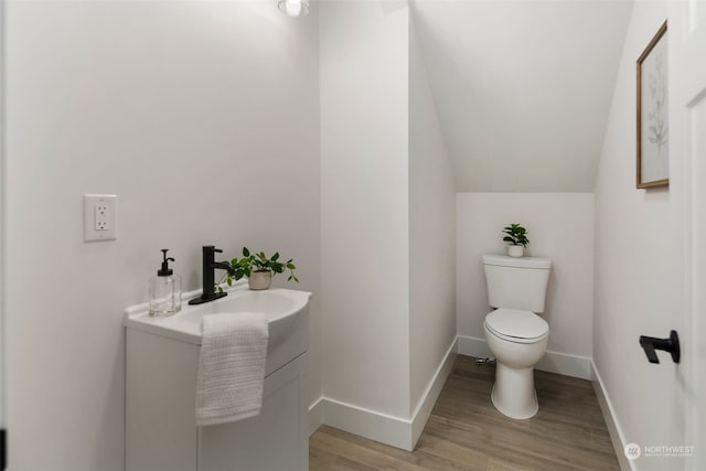 bathroom featuring hardwood / wood-style floors, vanity, toilet, and lofted ceiling