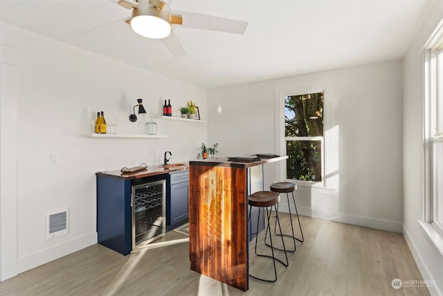 bar with blue cabinets, beverage cooler, plenty of natural light, and sink