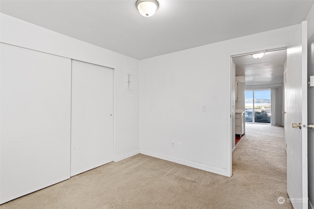 unfurnished bedroom featuring a closet and light carpet