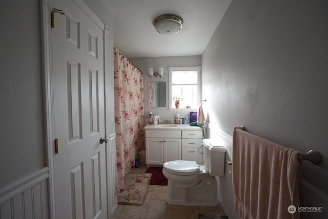 bathroom featuring toilet, walk in shower, vanity, and tile patterned floors