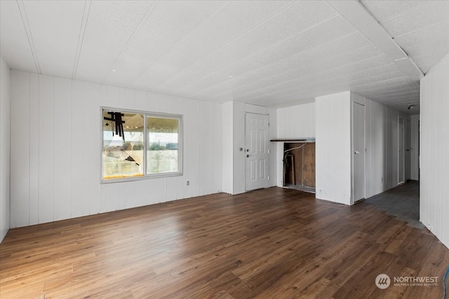 unfurnished living room with dark hardwood / wood-style floors and wood walls