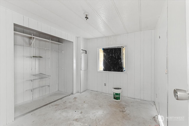 bathroom featuring concrete flooring and wood walls