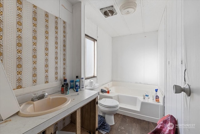 bathroom with toilet, a tub to relax in, vanity, and wood-type flooring