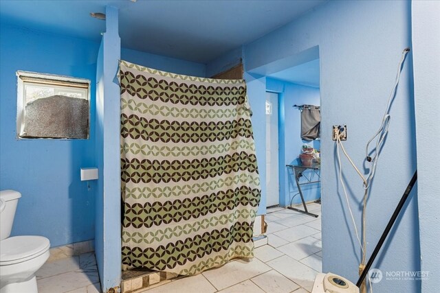 bathroom featuring tile patterned floors, curtained shower, and toilet