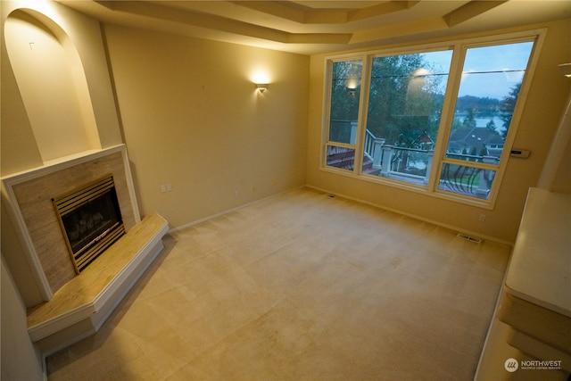 unfurnished living room featuring a raised ceiling and light colored carpet