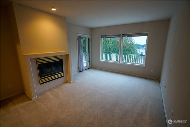 unfurnished living room featuring light carpet and a tiled fireplace