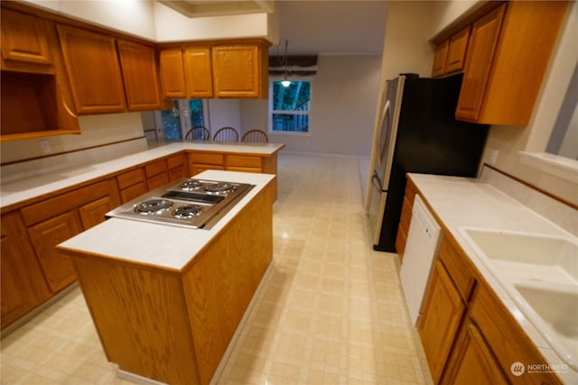 kitchen featuring sink, a kitchen island, kitchen peninsula, hanging light fixtures, and stainless steel appliances