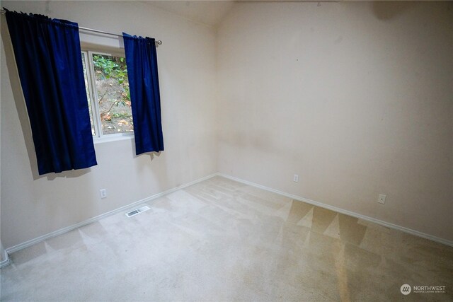 carpeted spare room featuring lofted ceiling