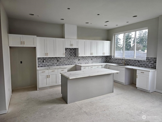 kitchen with white cabinets, decorative backsplash, sink, and a center island