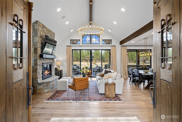 living room featuring beamed ceiling, light hardwood / wood-style floors, a fireplace, and a chandelier