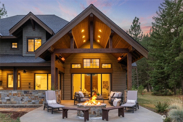 back house at dusk with a fire pit and a patio area