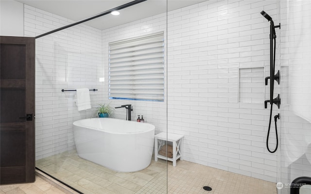 bathroom with tile patterned flooring, tile walls, and plus walk in shower