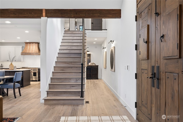 staircase with beamed ceiling and hardwood / wood-style flooring