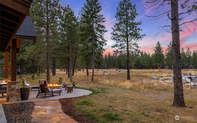 yard at dusk with an outdoor fire pit and a patio