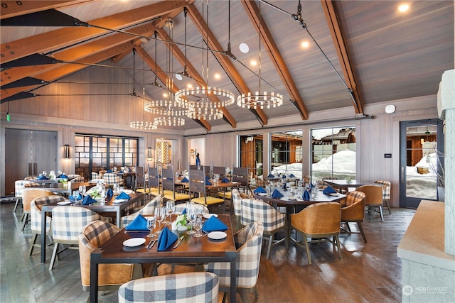 dining space with wood-type flooring, beam ceiling, high vaulted ceiling, a notable chandelier, and wood walls