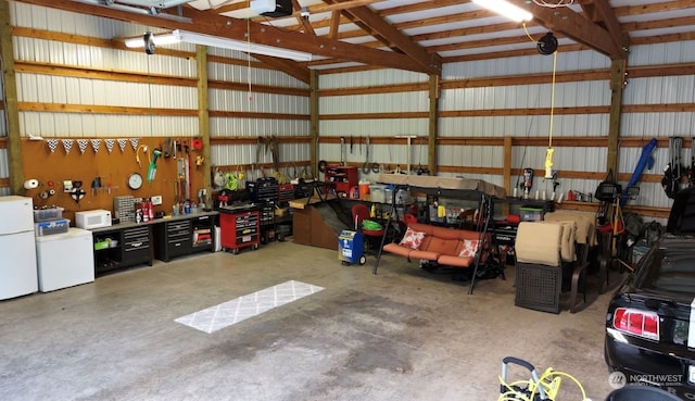 garage with a garage door opener, a workshop area, and white refrigerator