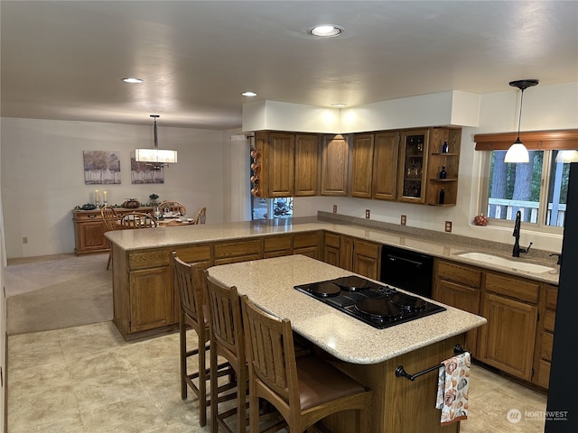 kitchen with a breakfast bar, black appliances, sink, and decorative light fixtures