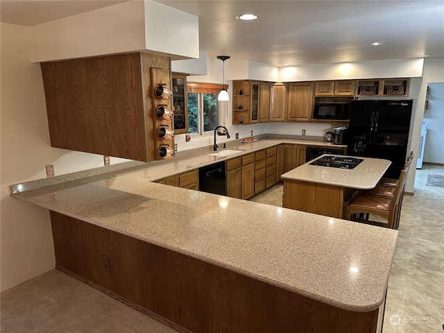 kitchen with kitchen peninsula, sink, black appliances, a breakfast bar, and pendant lighting