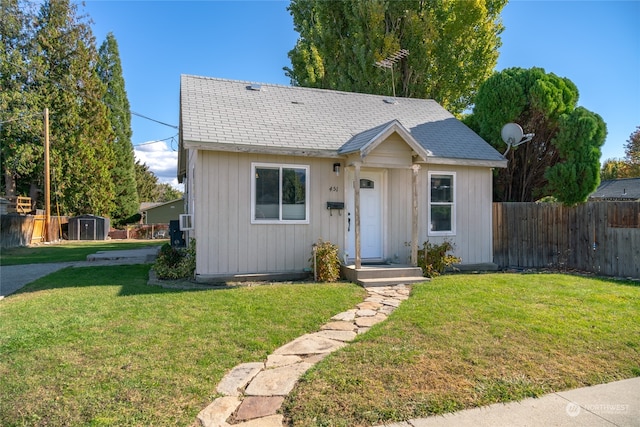 view of front of house featuring a storage unit and a front lawn