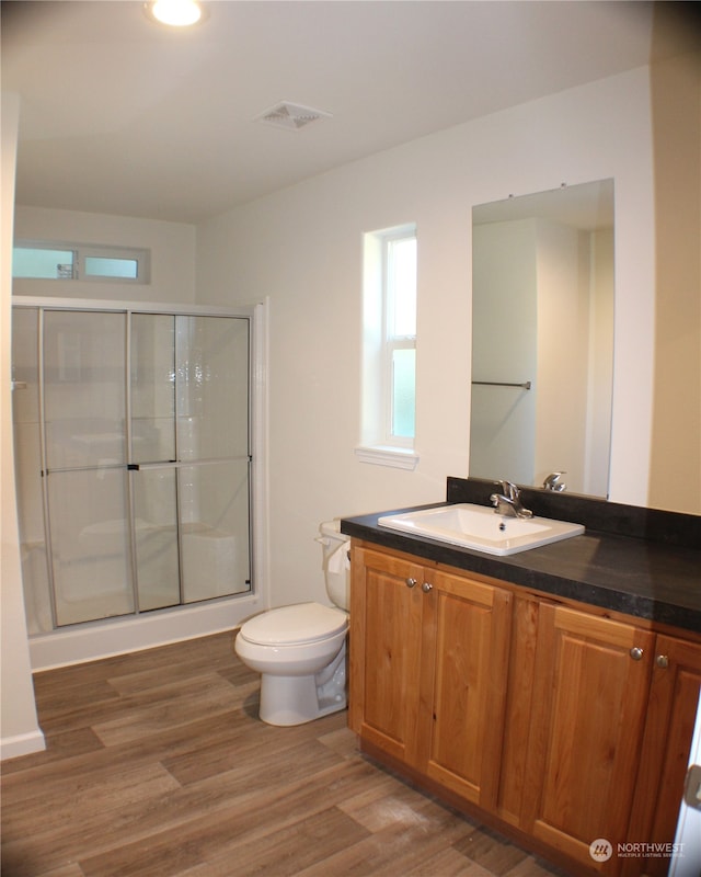 bathroom featuring vanity, hardwood / wood-style flooring, toilet, and an enclosed shower