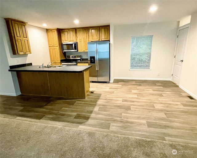 kitchen featuring appliances with stainless steel finishes, kitchen peninsula, sink, and light hardwood / wood-style floors