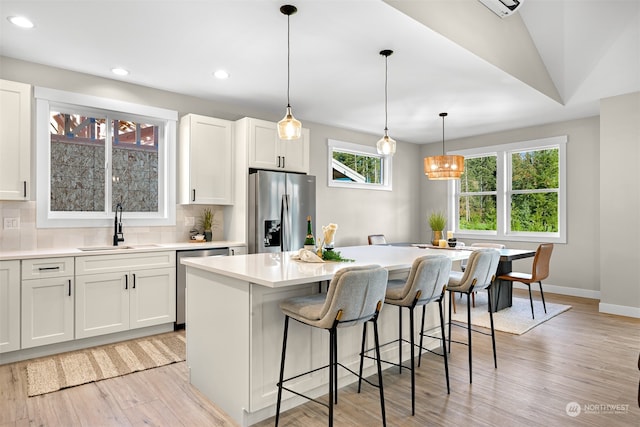 kitchen with appliances with stainless steel finishes, white cabinetry, a center island, and sink