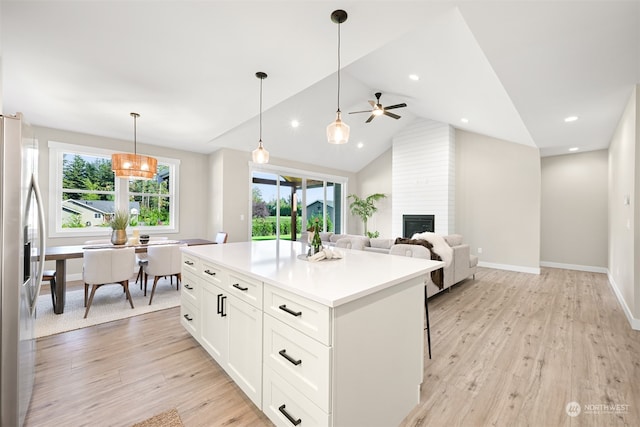 kitchen featuring lofted ceiling, white cabinets, light wood-type flooring, pendant lighting, and stainless steel refrigerator with ice dispenser