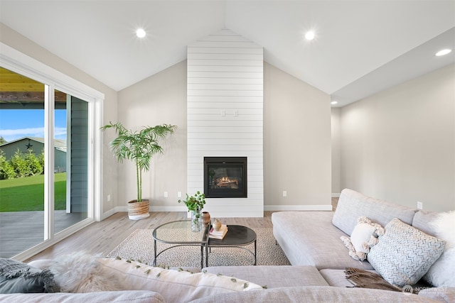 living room featuring a fireplace, light wood-type flooring, and vaulted ceiling