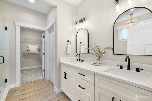 bathroom with a shower with door, hardwood / wood-style floors, and vanity