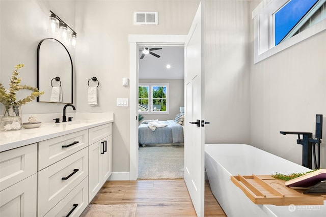 bathroom featuring vanity, hardwood / wood-style floors, a bath, and ceiling fan