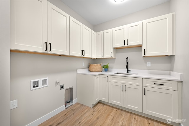 laundry area with sink, washer hookup, light wood-type flooring, and cabinets