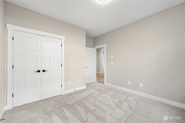 unfurnished bedroom featuring light colored carpet and a closet