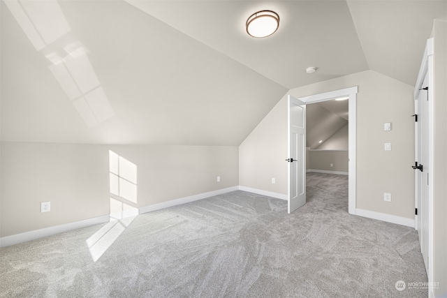 additional living space featuring lofted ceiling and light carpet