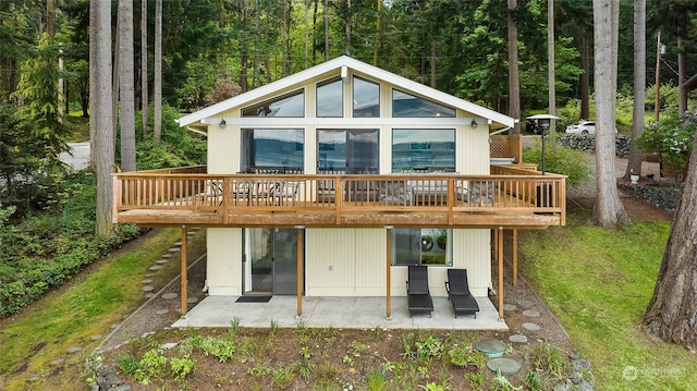 back of house with a wooden deck and a patio