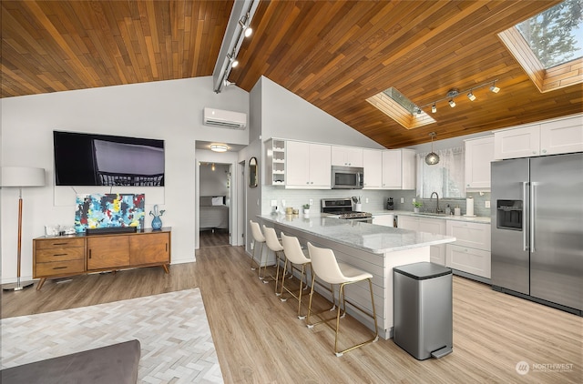 kitchen featuring a skylight, stainless steel appliances, pendant lighting, white cabinets, and track lighting