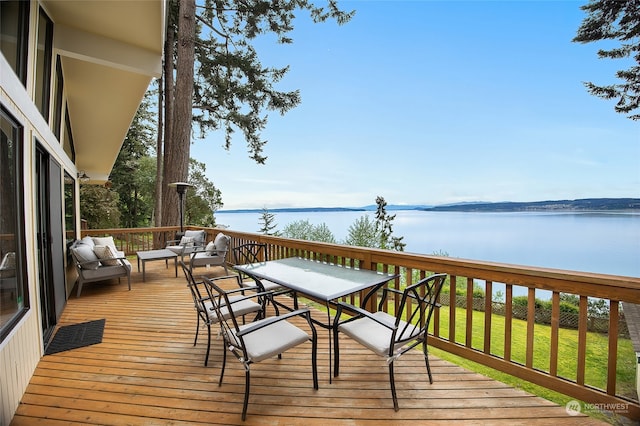 deck with a water view, an outdoor living space, and a yard