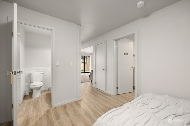 bedroom featuring a closet, ensuite bathroom, and light wood-type flooring