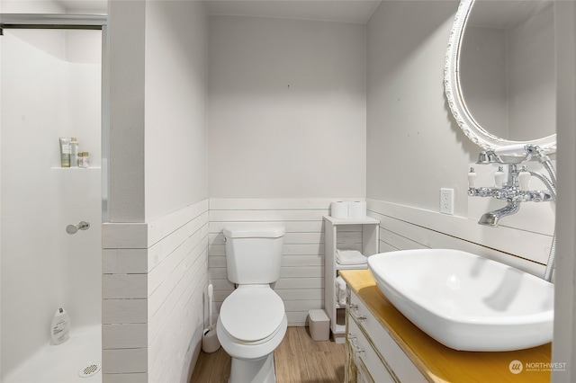 bathroom featuring vanity, toilet, wood-type flooring, and tile walls