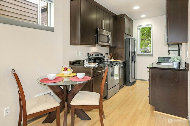 kitchen featuring sink, stainless steel appliances, dark brown cabinetry, and light hardwood / wood-style flooring