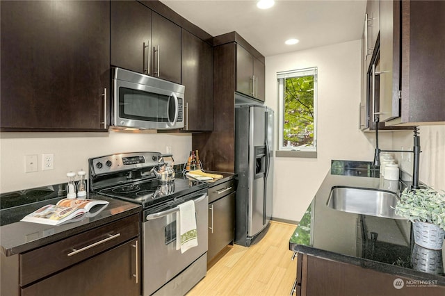 kitchen featuring light hardwood / wood-style flooring, dark brown cabinetry, stainless steel appliances, and dark stone counters