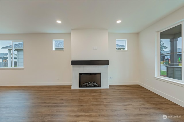 unfurnished living room featuring a fireplace, wood-type flooring, and plenty of natural light