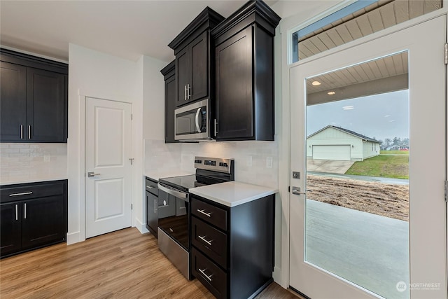 kitchen with appliances with stainless steel finishes, tasteful backsplash, and light hardwood / wood-style flooring